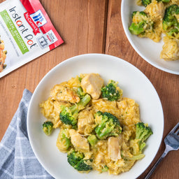A white bowl of McCormick Instant Pot Chicken Broccoli &amp; Rice with a fork on the side.