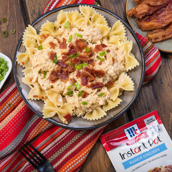 A bowl of pasta with chicken bacon and green onions topped with McCormick Instant Pot Ranch Chicken seasoning.