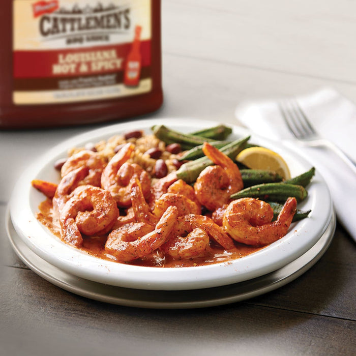 A plate of shrimp rice and okra with a bottle of Cattlemens Louisiana Hot &amp; Spicy sauce in the background.
