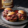 Three mini beef sandwiches with red cabbage slaw and Cattlemens BBQ sauce on a silver plate.