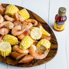 A wooden bowl filled with shrimp corn on the cob sausage and a bottle of Zatarains Shrimp &amp; Crab Boil.