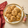 A plate of pecan cookies with a bottle of McCormick cinnamon sugar on a table.