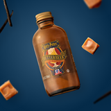 Bottle of Harry Potter Butterbeer extract with caramel pieces on a blue background