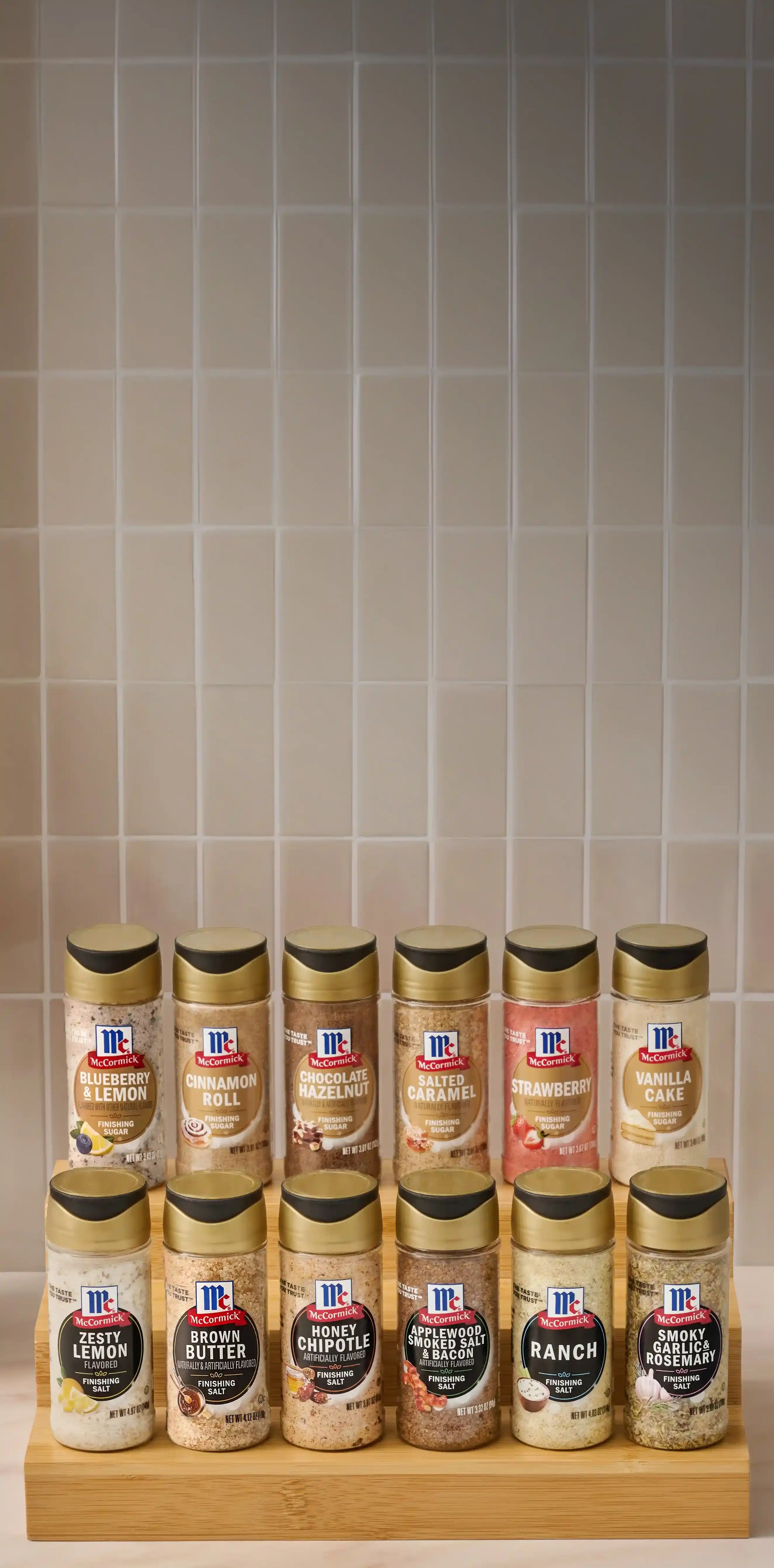 Row of McCormick seasoning bottles on a wooden block against a tiled wall.