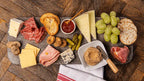 Platter of assorted meats, cheeses, and fruits on a wooden surface