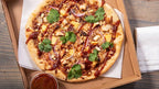 BBQ chicken pizza in a cardboard box on a wooden table