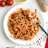 A plate of spaghetti with shrimp tomato sauce and parmesan cheese.