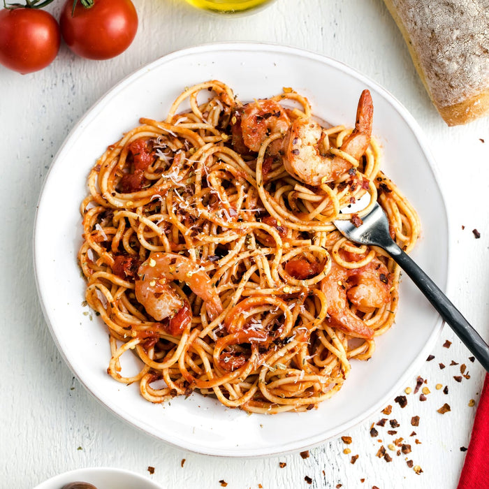 A plate of spaghetti with shrimp tomato sauce and parmesan cheese.