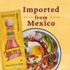 A packet of Cholula hot sauce next to a plate of Mexican chilaquiles with a fried egg avocado and crema.