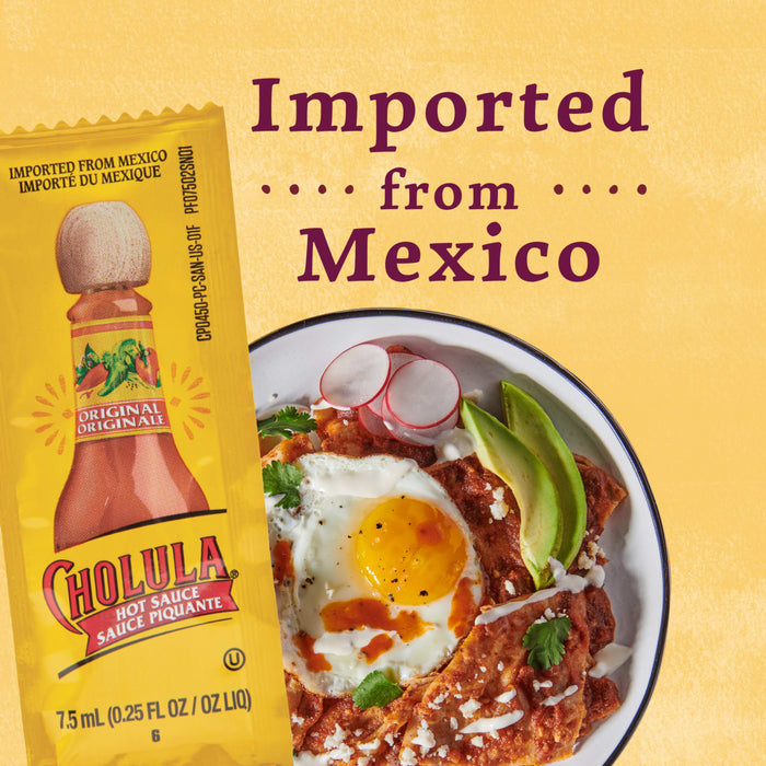 A packet of Cholula hot sauce next to a plate of Mexican chilaquiles with a fried egg avocado and crema.