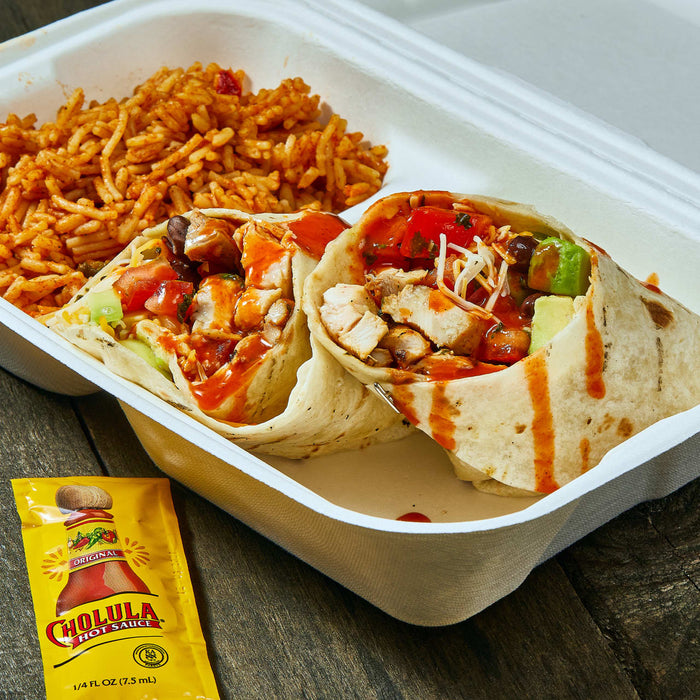 A white takeout container with two chicken burritos a side of rice and a packet of Cholula hot sauce.