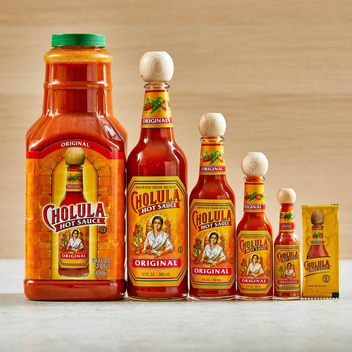 Six bottles of Cholula Original Hot Sauce in different sizes from a small packet to a large bottle.