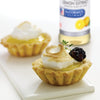 Two lemon tarts with meringue and a blackberry on top, with a bottle of McCormick Culinary Lemon Extract in the background.