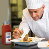 A chef is garnishing a plate of salmon with dill next to a jar of McCormick Smoked Paprika.