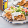 A plate of Old Bay Rub crusted salmon with a side salad and a dollop of creamy sauce.