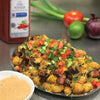 A plate of tater tots topped with steak cheese tomatoes and green onions.