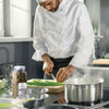 A chef is preparing a meal in a kitchen with a pot of boiling water on the stove and a jar of McCormick Whole Bay Leaves.