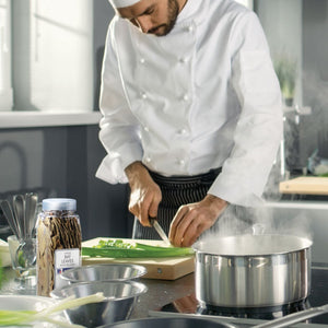 A chef is preparing a meal in a kitchen with a pot of boiling water on the stove and a jar of McCormick Whole Bay Leaves.
