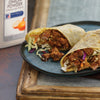 Two wraps filled with meat and vegetables are on a blue plate.