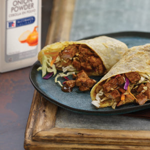 Two wraps filled with meat and vegetables are on a blue plate.