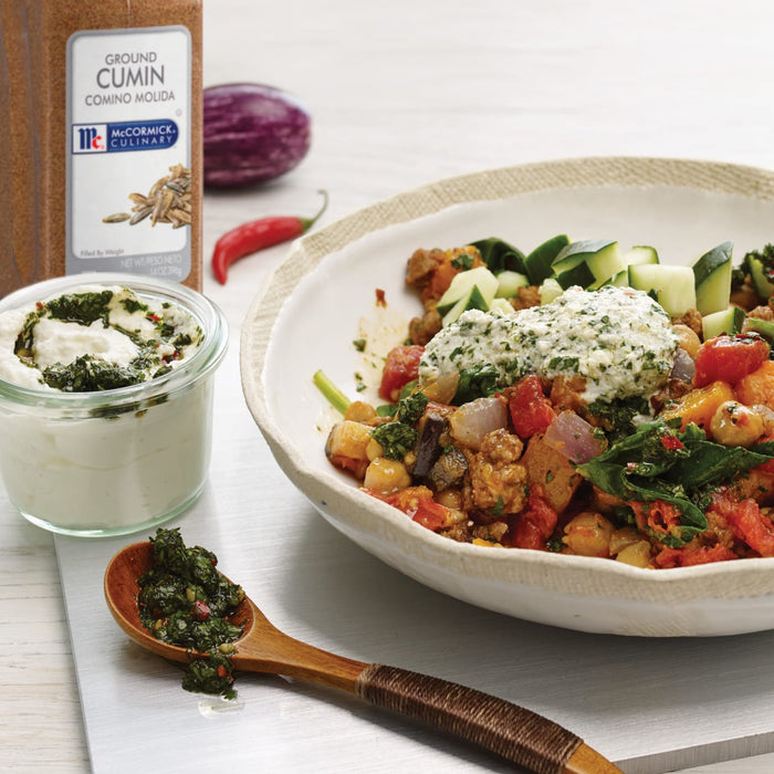 A bowl of Mediterranean-style stew with a dollop of yogurt and a side of McCormick Ground Cumin.