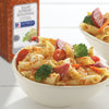 A bowl of pasta salad with salami tomatoes broccoli and carrots seasoned with McCormick Salad Supreme seasoning.