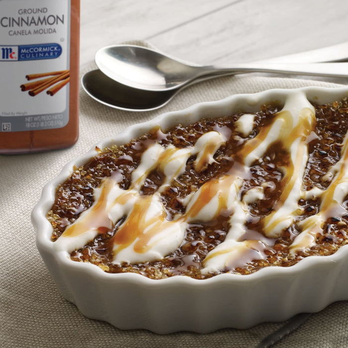 A close-up of a small white ramekin filled with a creamy dessert topped with caramel and a McCormick Culinary Ground Cinnamon label.