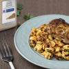 A plate of food with a piece of grilled fish on top of a bed of pasta with a McCormick Culinary Ground White Pepper container in the background.