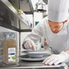 A chef in a white uniform and gloves is garnishing a dish with a sprig of thyme next to a jar of McCormick Italian Seasoning.