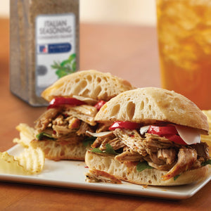 Two Italian-seasoned pulled pork sandwiches on ciabatta rolls with red peppers and provolone cheese.