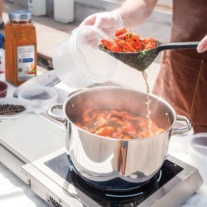 A person is adding crawfish to a pot of boiling water on a stovetop.