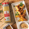 A jar of Lawrys Garlic Powder next to a plate of seasoned potato wedges and a small bowl of dip.