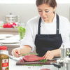 A chef is preparing a piece of meat with rosemary and Lamberts Pepper Supreme seasoning.