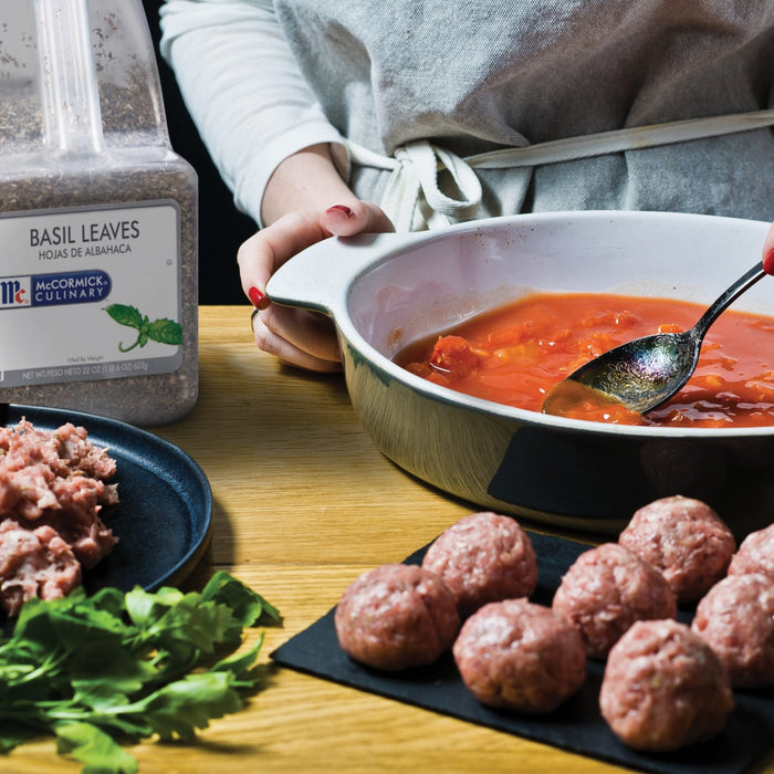 A person is preparing a meal with McCormick Culinary Basil Leaves ground meat and meatballs.