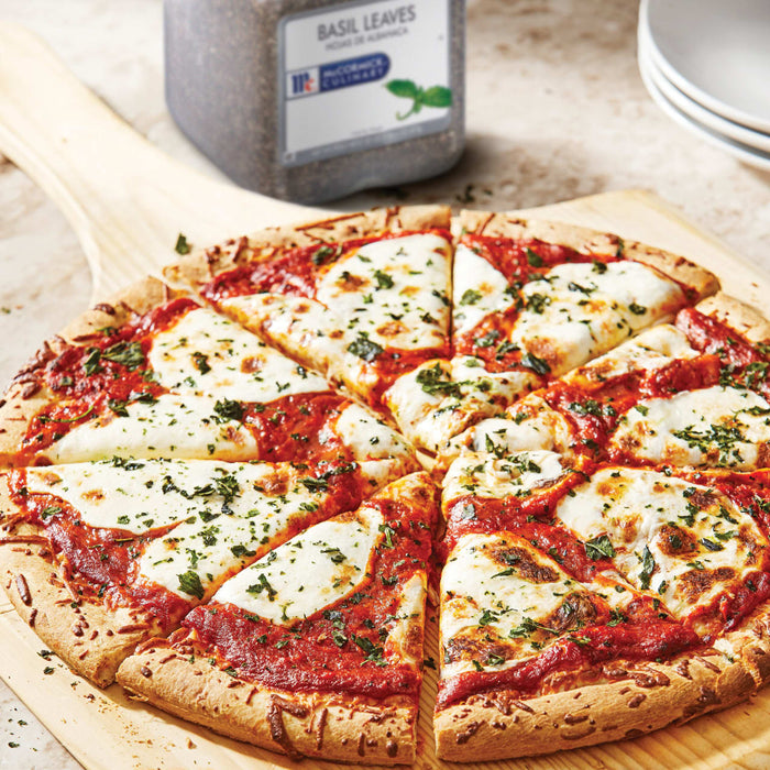 A close-up of a pizza with mozzarella cheese tomato sauce and basil leaves on a wooden cutting board.