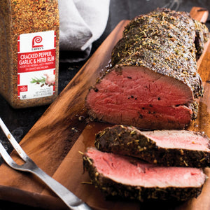 A close-up of a Lawrys Cracked Pepper Garlic &amp; Herb Rub seasoned roast beef on a wooden cutting board.