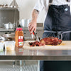 A chef is using tongs to pull apart a piece of Lawrys Sweet Basil Citrus &amp; Garlic Rub seasoned meat.
