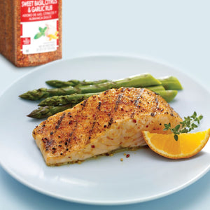 A plate of grilled salmon with asparagus and a slice of orange seasoned with Sweet Basil Citrus &amp; Garlic Rub.