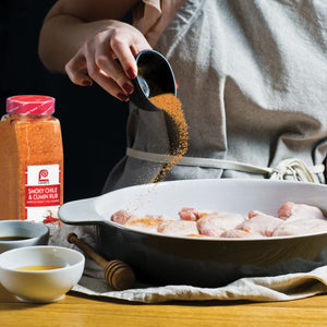 A hand sprinkles Lawrys Smoky Chile &amp; Cumin Rub onto chicken in a bowl.