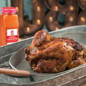 A roasted chicken seasoned with a Chipotle Cinnamon Rub sits in a metal pan.