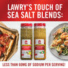 Two bottles of Lawrys Touch of Sea Salt blends one Mediterranean and one Roasted Garlic with a plate of food in the background.