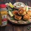 A jar of Lawrys Touch of Sea Salt Roasted Garlic Seasoning next to a plate of fried food.