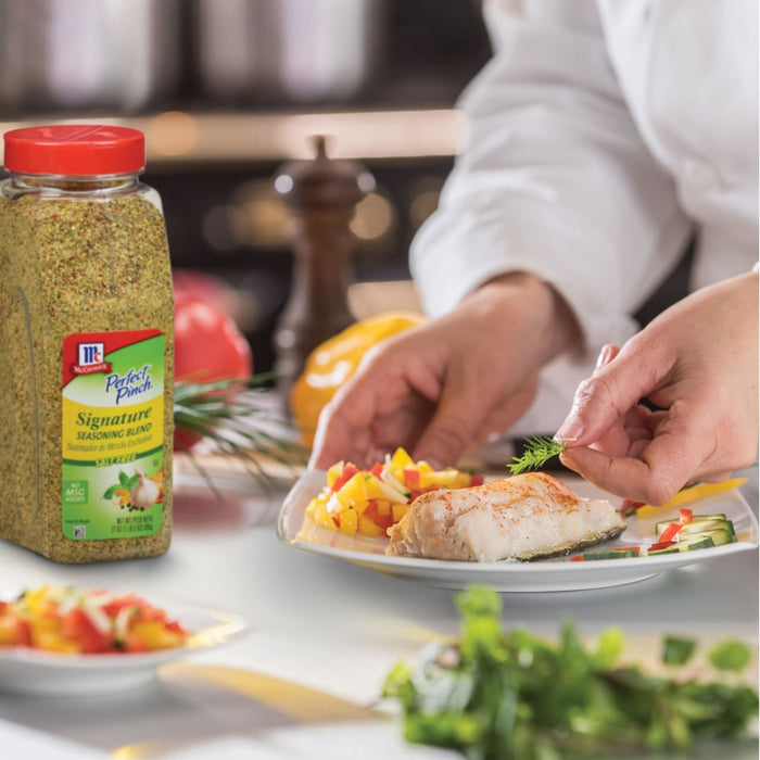 A chef is garnishing a plate of fish with a sprig of dill using McCormick Perfect Pinch Signature Seasoning Blend.