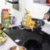 A person is cooking vegetables in a pan on a stovetop using McCormick Perfect Pinch Garlic &amp; Herb seasoning.
