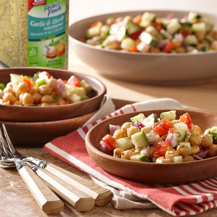 A bowl of Perfect Pinch Garlic &amp; Herb Seasoning chickpea salad with cucumbers tomatoes and red onions.