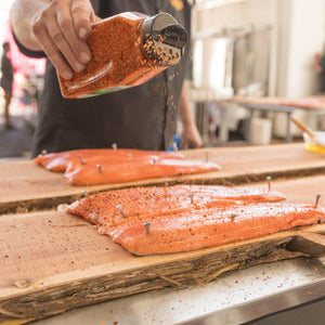 A person is seasoning salmon fillets with a spice blend.