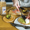 A person is preparing a meal with a poached egg avocado and toast using McCormick Culinary Everything Bagel Seasoning.