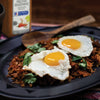 A plate of Peruvian-style rice with two fried eggs and cilantro with a bottle of McCormick Peruvian Seasoning in the background.