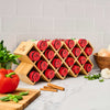 A bamboo spice rack from Gneiss Spice displays red-labeled spice jars on a kitchen counter.