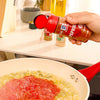 A hand sprinkles McCormick Paprika into a pan of tomato sauce.